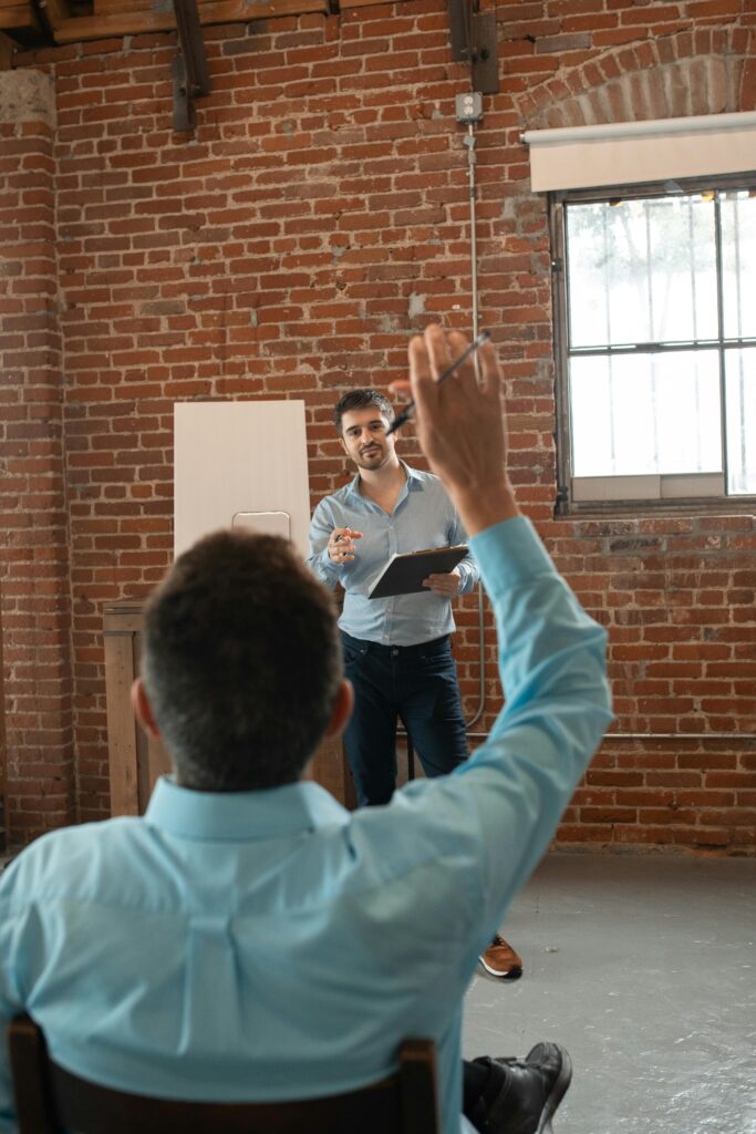 Adult learners in a classroom engaging with a teacher during an interactive session.